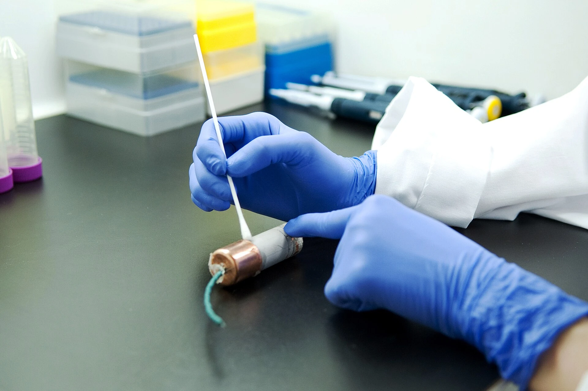 Forensisch onderzoeker met handschoenen bemonstert sporen in een lab
