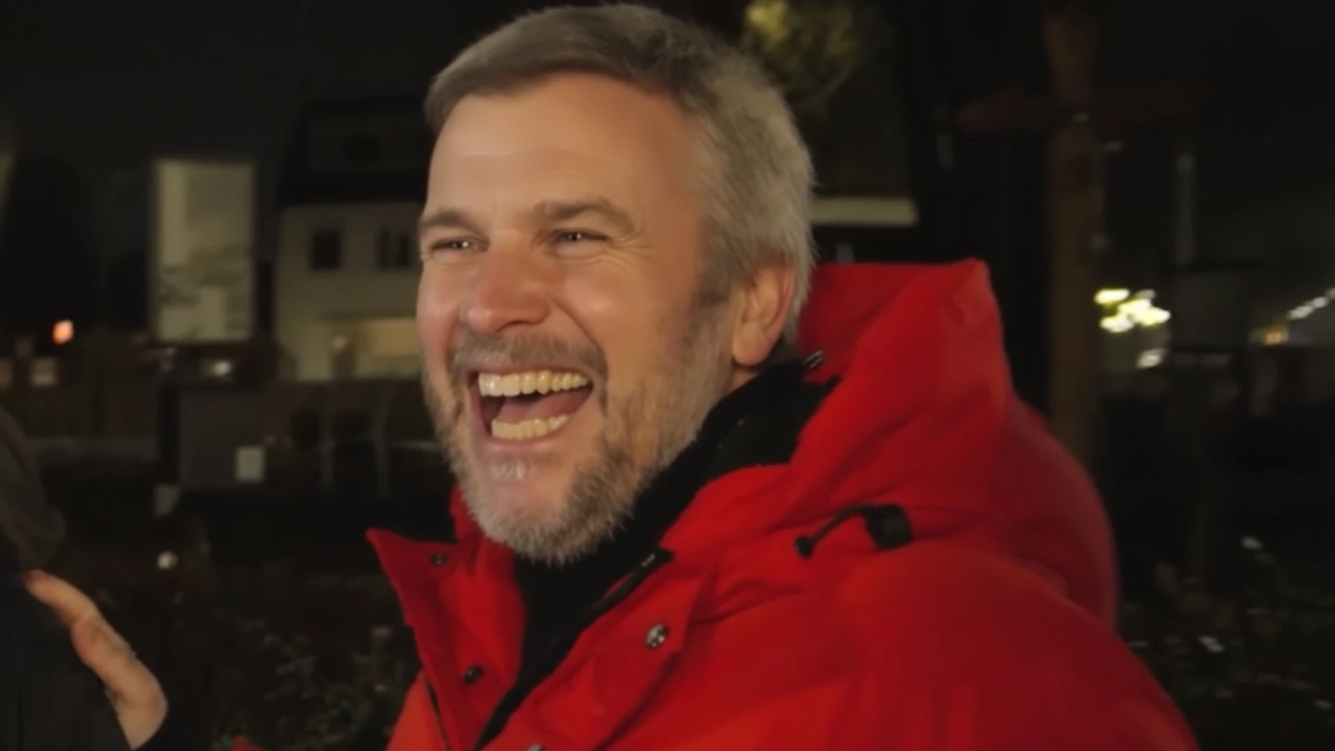 Winston Gerschtanowitz lachend in rode jas in de avond