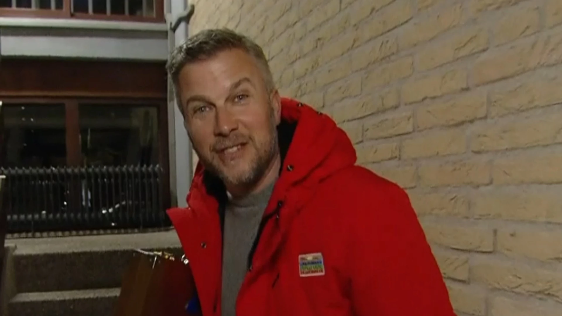 Winston Gerschtanowitz in rode jas bij een voordeur